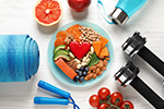 Bowl mit Obst darum angeordnet liegen Fitnessgeräte